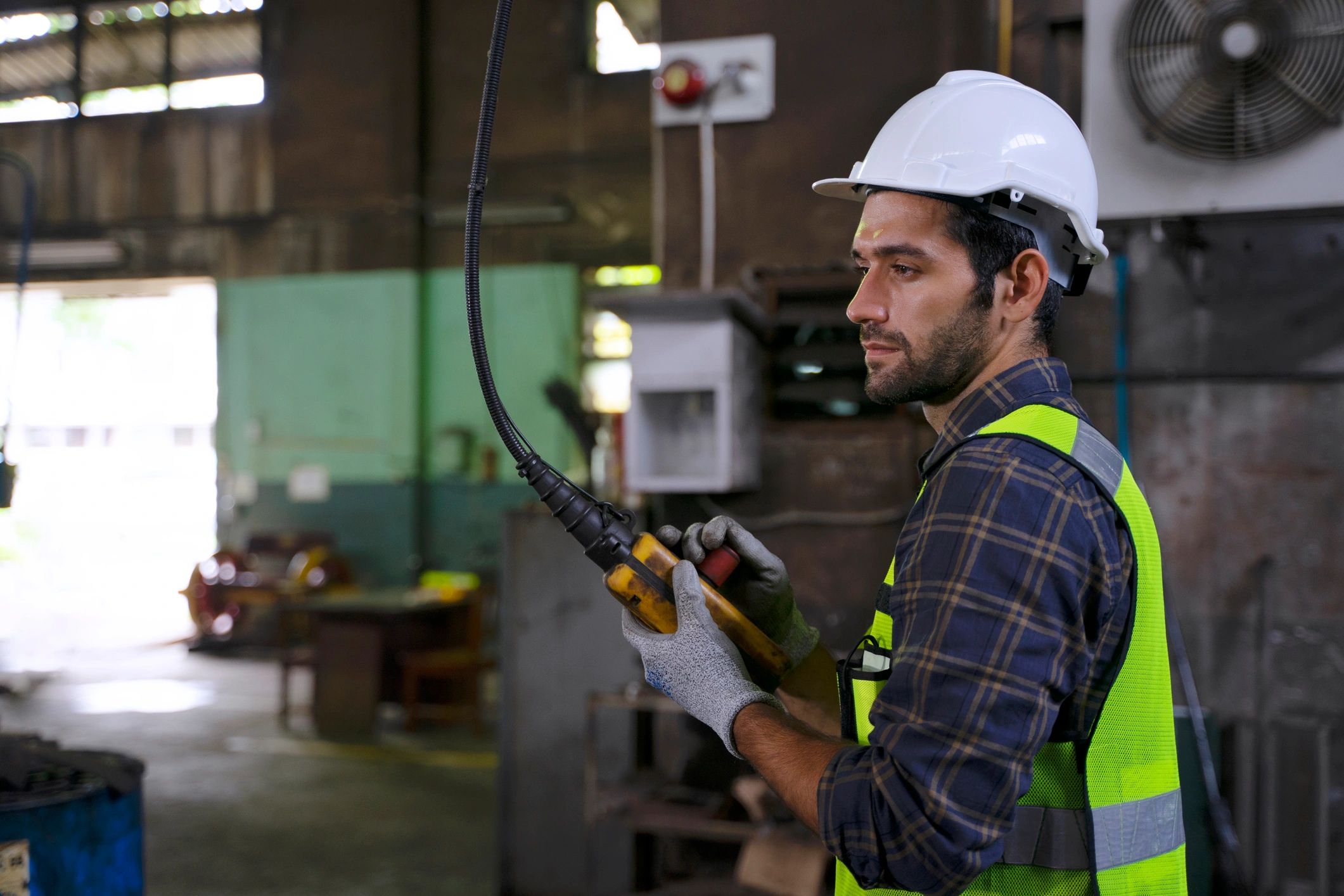 Industrial worker inspecting machinery in a factory environment